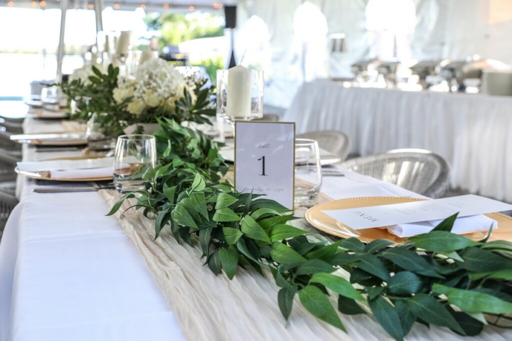 a place card reading Table 1 on a table with a leafy garland and gauze runner